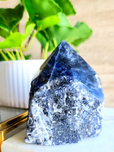 Load image into Gallery viewer, Indulge in the tranquility of Sodalite – a calming gem that enhances mental clarity, communication, and confidence. Its soothing essence promotes rest and mindfulness, empowering you to make decisions with ease and express yourself openly

